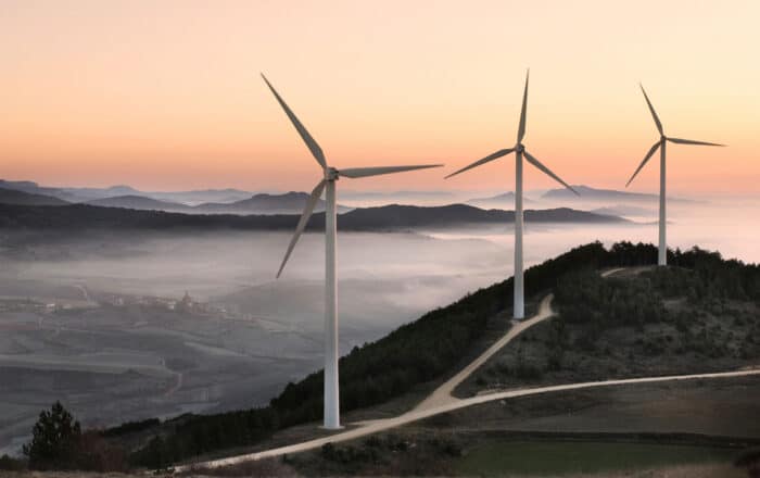 Wind turbines up on a hill with fog in the background
