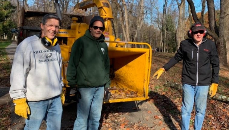 men standing in front of wood chipper | Bentley Systems | Infrastructure Engineering Software Company men standing in front of wood chipper