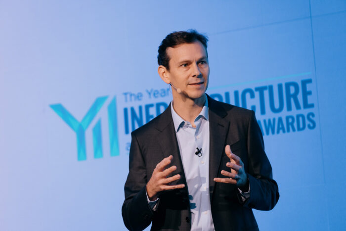 Nicholas Cumins, the CEO of Bentley Systems, speaks on stage in a suit, gesturing with both hands. | Bentley Systems | Infrastructure Engineering Software Company Nicholas Cumins, the CEO of Bentley Systems, speaks on stage in a suit, gesturing with both hands.