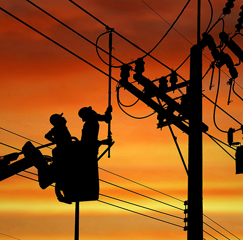 Silhouette two electricians with disconnect stick tool on crane truck are working to install electrical transmission on power pole stock photo | Bentley Systems | Infrastructure Engineering Software Company Silhouette two electricians with disconnect stick tool on crane truck are working to install electrical transmission on power pole stock photo